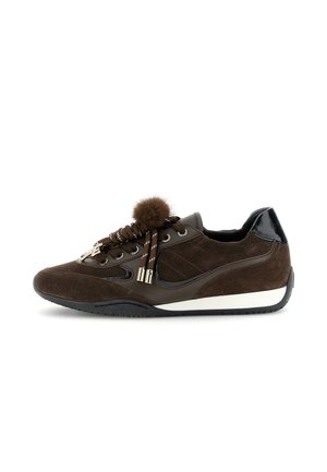 Sneaker in suede marrone con tallone in vernice nera, spessi lacci marroni sormontati da un pompon di pelliccia e suola nera bordata di bianco.