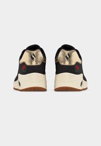 Paire de baskets noires avec des semelles blanches épaisses, des accents dorés au talon, une broderie d'une rose rouge sur les côtés, vues de dos.