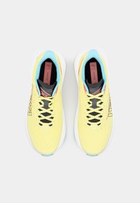 Des chaussures de course jaunes avec une tige en mesh respirant, des lacets noirs et des accents bleus, offrant une semelle texturée et un logo sur le côté.