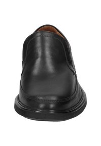 Black leather slip-on shoe featuring a rounded toe, smooth texture, and minimal stitching detail along the sides. Flat rubber sole.