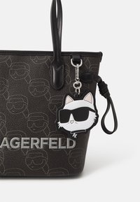 Borsa a tote in pelle nera con motivo a faccia in rilievo, logo argentato e un portachiavi a forma di gatto dei cartoni animati con occhiali da sole staccabile.