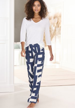 White V-neck top paired with navy, patterned wide-leg pants featuring large white graphic shapes. Smooth fabric texture, casual design.