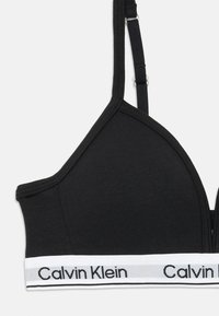 Crni bralette trokutastog oblika, napravljen od mekog materijala, s bijelim Calvin Klein logotipom i podesivim naramenicama.