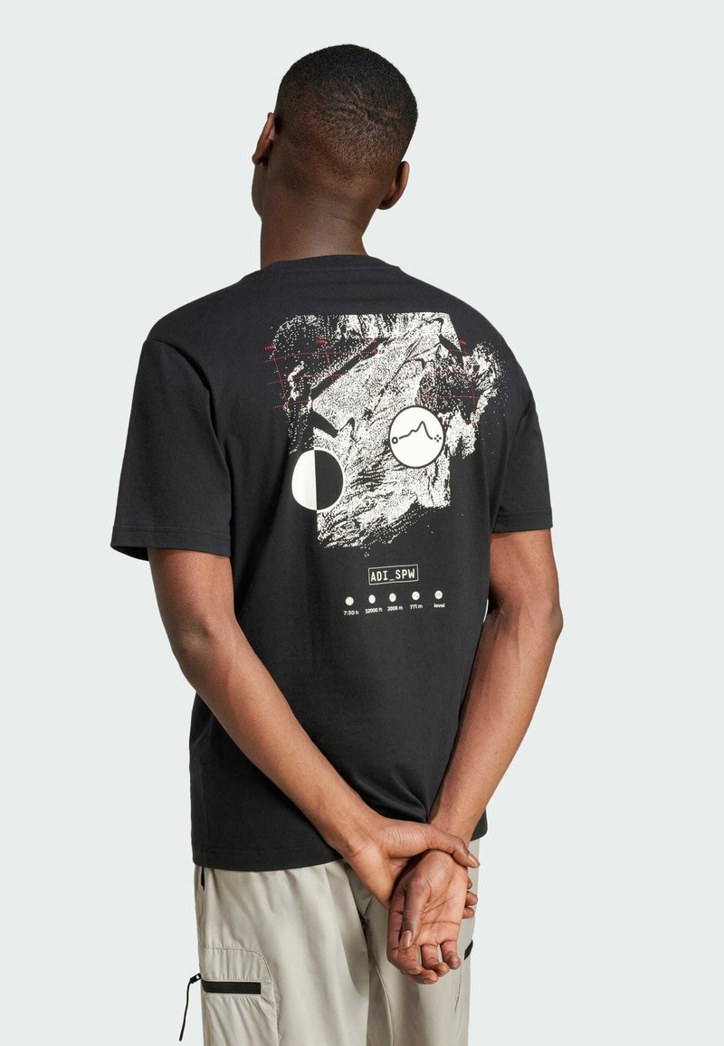 Svart bomull T-shirt med en grafisk design på baksidan som har vita och röda abstrakta former, text och ett geometriskt mönster.