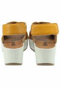 Sandali platform in pelle gialla con finitura liscia, cinturino con chiusura a strappo e suola bianca con superficie testurizzata.