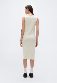 Ανοιχτό γκρι, αμάνικο, μίντι φόρεμα με εφαρμοστή σιλουέτα. Ομαλή υφή, καμπυλωτή λαιμόκοψη και τελείωμα κάτω από το γόνατο.