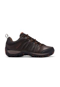 Zapato de senderismo bajo en tonos marrón y negro con suela rugged, parte delantera con cordones y marca Columbia en el costado y el talón.