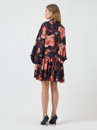 Sukienka w kwiaty z intensywnymi pomarańczowymi i ciemnopurpurowymi kwiatami na czarnym tle, z falbaną na dole, luźnym krojem i długimi rękawami.