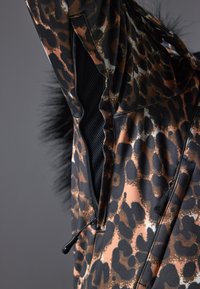Leopardmønstret vest laget av glatt stoff med sorte nettingdetaljer og en kunstpelskant. Har glidelåslommer og justerbare snorer.