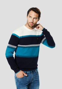 Navy blue and teal striped sweater with a round neckline, textured knit, ribbed cuffs and hem, featuring a small logo detail on the chest.