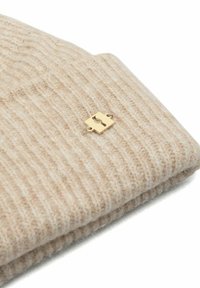 Beżowa dziana czapka beanie wykonana z miękkiego materiału, z prążkowaną teksturą i złotym metalowym detalem.