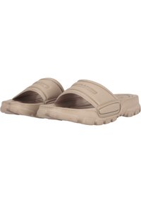 Beige slip-on sandals with a thick textured sole, wide straps, and subtle branding on the upper. Rounded shape enhances comfort and fit.