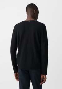 Czarny sweter z długim rękawem, wykonany z teksturowanej dzianiny. Klasyczny okrągły dekolt, prosty dół oraz minimalne detale z tyłu.