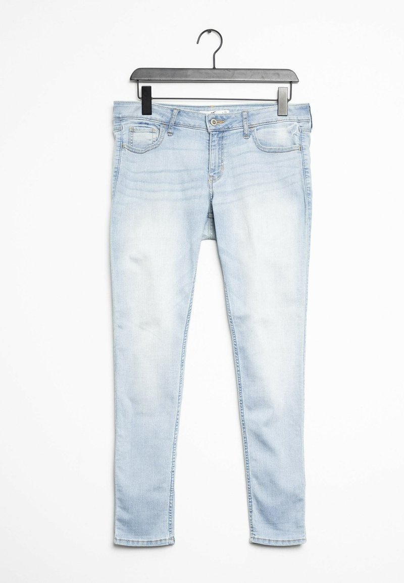 Jeans ajustados de color azul claro con un lavado desgastado, diseño de cinco bolsillos, pasadores para cinturón, cierre de cremallera y botón metálico. Textura de denim suave.