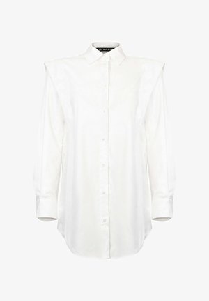 Balti marškiniai su traškiu apykakle, ilgomis rankovėmis ir petnešėmis. Lygus audinys su šiek tiek struktūruota forma ir apvaliu kraštu.