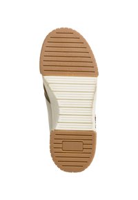 Semelle en caoutchouc marron et blanche avec un motif de grip texturé, présentant des rainures horizontales et verticales pour une traction et une stabilité accrues.