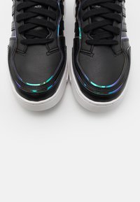 Svarta lädersneakers med iriserande detaljer längs sömmarna, platta svarta skosnören och vita gummisulor.