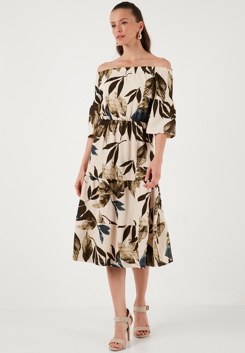 Off-the-shoulder dress made of lightweight fabric, featuring a cream base with dark green and blue leaf patterns, and a cinched waist.
