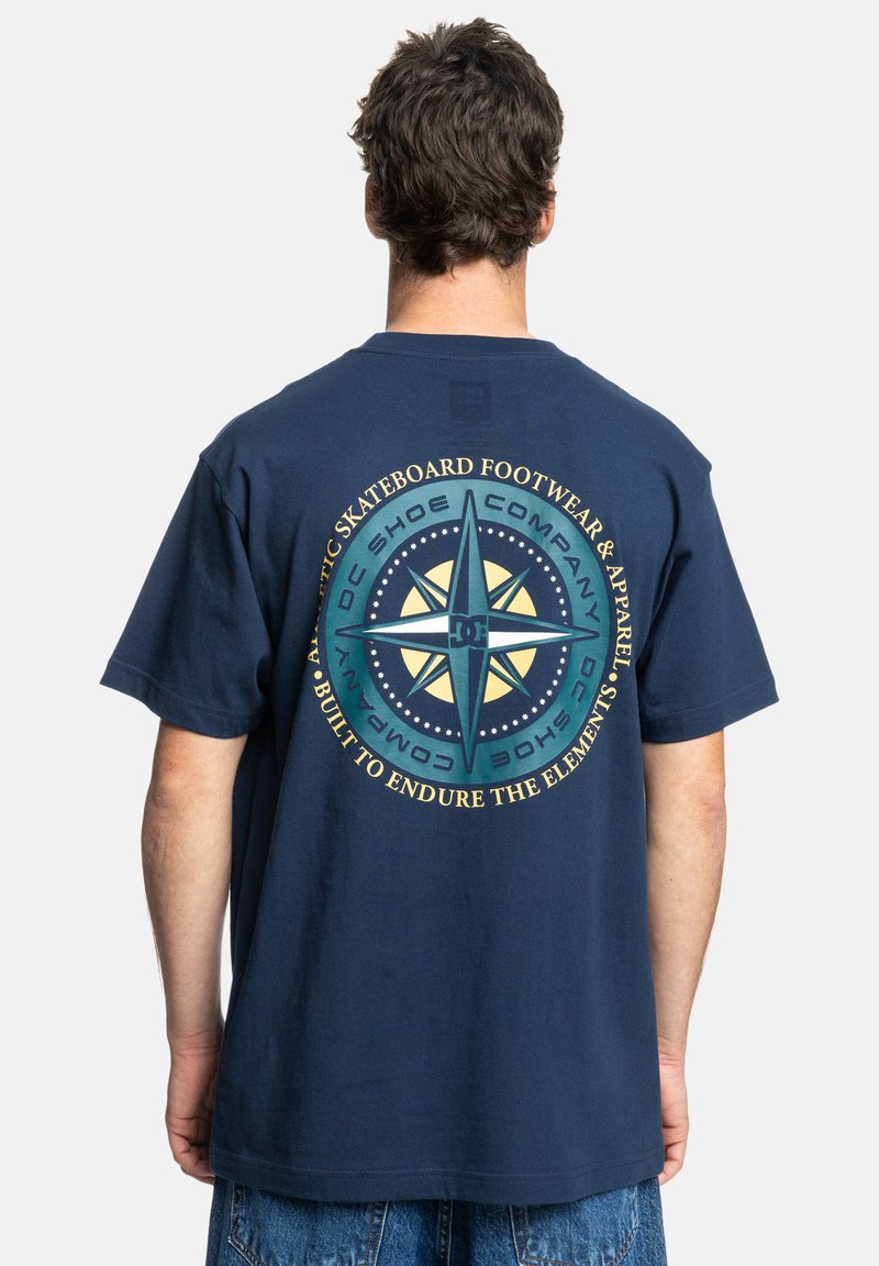 Navy blue cotton t-shirt featuring a large compass graphic on the back, with text and star details in yellow and turquoise accents.
