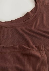 Bruine sportieve tanktop met een ronde halslijn, textuurstof met subtiele strepen en versterkte stiksels aan de randen.