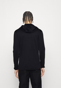 Felpa con cappuccio nera, maniche lunghe, texture morbida e design semplice. Presenta una vestibilità comoda senza loghi o pattern visibili.