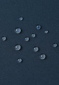 Tessuto di un blu scuro con una texture, con chiare gocce d'acqua disperse sulla superficie, che evidenziano le proprietà impermeabili o resistenti all'acqua.