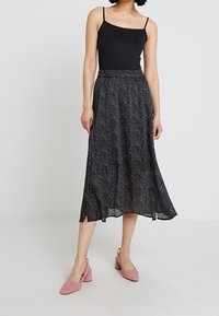 Černá midi sukně s tečkovaným vzorem v bílé barvě, lehká látka, elastický pás, spárovaná s černým tílkem a růžovými lodičkami na blokovém podpatku.