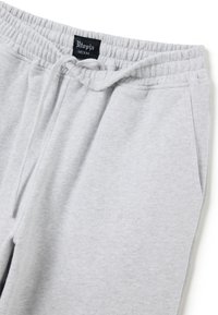 Pantalones de chándal gris claro, hechos de una tela suave, con una cinturilla elástica, cordón ajustable y un sutil logo bordado en el frente.