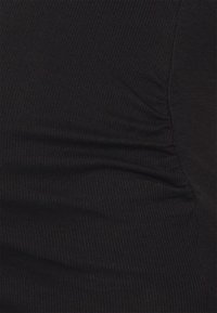 Svart ribbat tyg med subtila rynkdetaljer på ena sidan, som visar en texturerad yta och en tight passform, lämplig för åtsittande kläder.