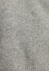 Tejido de punto gris con un patrón texturizado, exhibiendo diferentes tonos de gris. El material parece suave y cálido, con un borde acanalado.