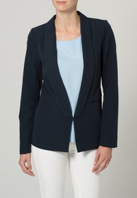 Mörkblå kavaj med sjalkrage och enknapplistning, med en figursydd design och långa ärmar, tillsammans med en ljusblå blus.