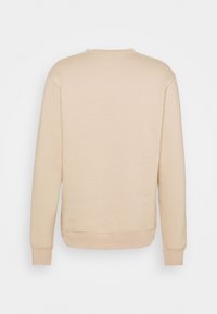 Sweat-shirt beige à manches longues avec poignets et bas côtelés, montré de dos sur un fond uni.