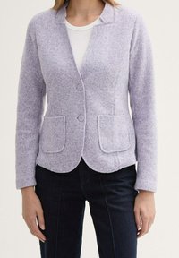 Lila ullblandad kavaj med slidkrage, två framfickor och rundad nederkant; har knäppningar med knappar och strukturerad tyg.