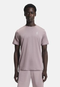 Vaalean violetti urheilupaita, jossa on pyöreä kaula-aukko, lyhyet hihat ja pieni valkoinen logo vasemmassa rinnassa, valmistettu sileästä, joustavasta materiaalista.