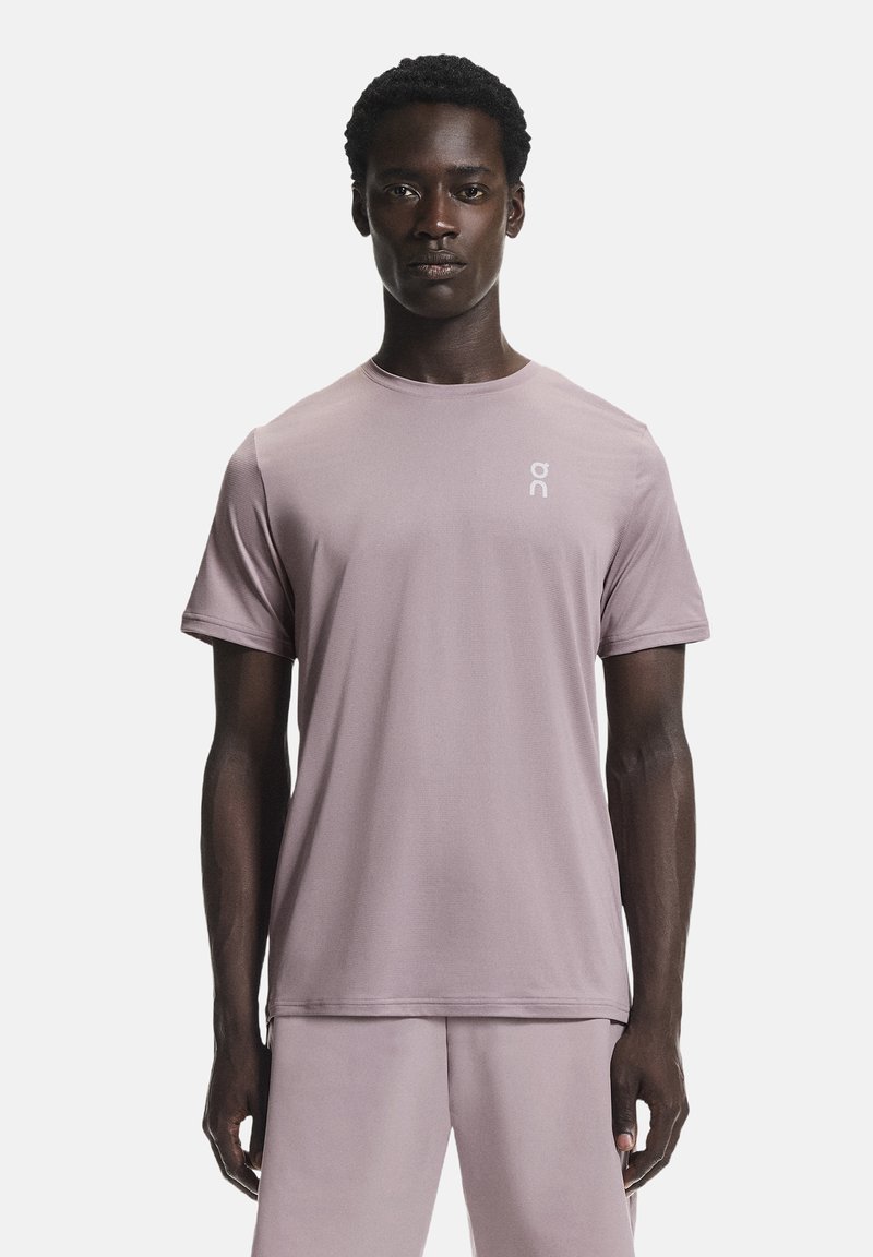 Vaalean violetti urheilupaita, jossa on pyöreä kaula-aukko, lyhyet hihat ja pieni valkoinen logo vasemmassa rinnassa, valmistettu sileästä, joustavasta materiaalista.