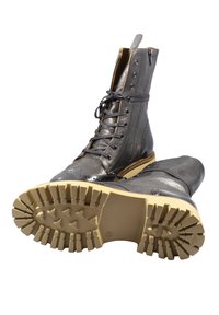 Stivali grigi in pelle alta alla caviglia con chiusura a lacci, caratterizzati da una tomaia testurizzata, dettagli brogue e una suola robusta in gomma beige.