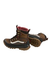 Scarpe da trekking marroni e nere con fodera interna rossa, striscia laterale bianca, suole robuste e occhielli metallici per i lacci, posizionate su uno sfondo bianco.