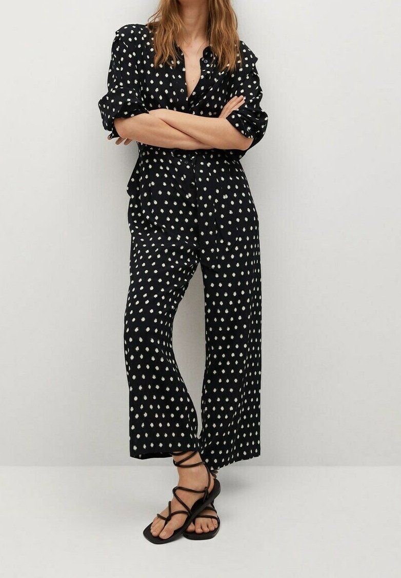 Ensemble chemise noire à pois et pantalon à jambes larges. Tissu doux à pois blancs, design boutonné, manches retroussées, assorti à des sandales noires.