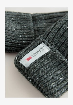 Tummanharmaa neulottu myssy, jossa on railsimainen pinta. Varustettu valkoisella tarralla, jossa lukee "3M THINSULATE" eristykselle.