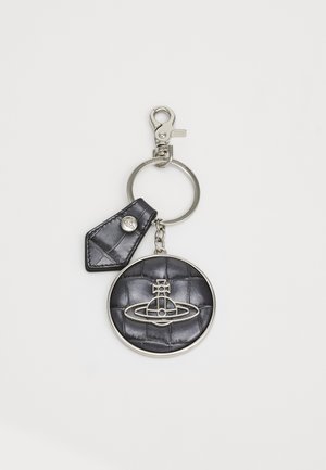 Porte-clés en cuir matelassé noir avec un charm circulaire et quincaillerie métallique. Il présente un design de logo et une sangle détachable avec un bouton-pression.