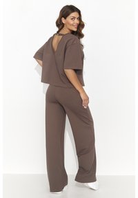 Brązowy dwu-elementowy zestaw loungewear wykonany z miękkiego materiału. Kwadratowy krótki top z odkrytymi plecami oraz spodnie w szerokim kroju, gładka tekstura, luźny krój.