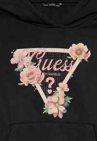 Sudadera negra con un diseño gráfico floral que incluye flores rosas, una forma triangular y el texto "Guess Los Angeles" en letras decorativas.