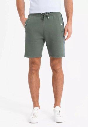 Shorts en mélange de coton vert avec une taille élastique, cordon de serrage, poches latérales et bandes latérales bleu marine. Coupe ajustée, longueur mi-cuisse.