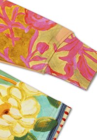 Bloemmotiefstof met levendige kleuren, waaronder roze en geel. Heeft een zachte textuur en zichtbare stiksels aan de randen.