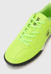 Baskets vert fluo avec tige synthétique lisse, lacets texturés, semelle extérieure noire et col rembourré ; présente des détails de couture subtils.