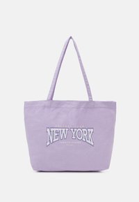 Sac fourre-tout en toile violette avec deux anses, arborant "NEW YORK" en lettres blanches et dorées en gras sur le devant. Texture lisse, design simple.