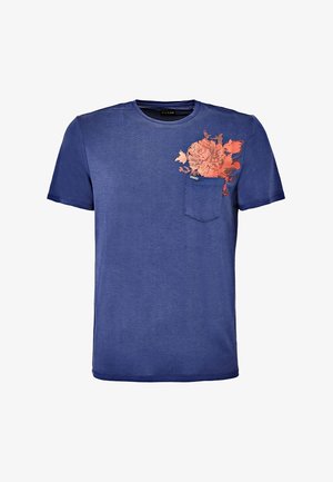 Blå kortærmet T-shirt i et blødt stof, med et pink blomsterdesign på venstre bryst og en lille lomme.