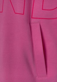 Sweatshirt fuchsia avec une poche avant, texture lisse et grandes lettres roses sur la poitrine.