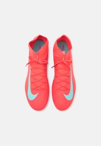 Încălțăminte de fotbal Nike în nuanță de corai strălucitor, cu un exterior texturat, accente turqoise și șireturi plate. Design elegant cu o guler scăzut.
