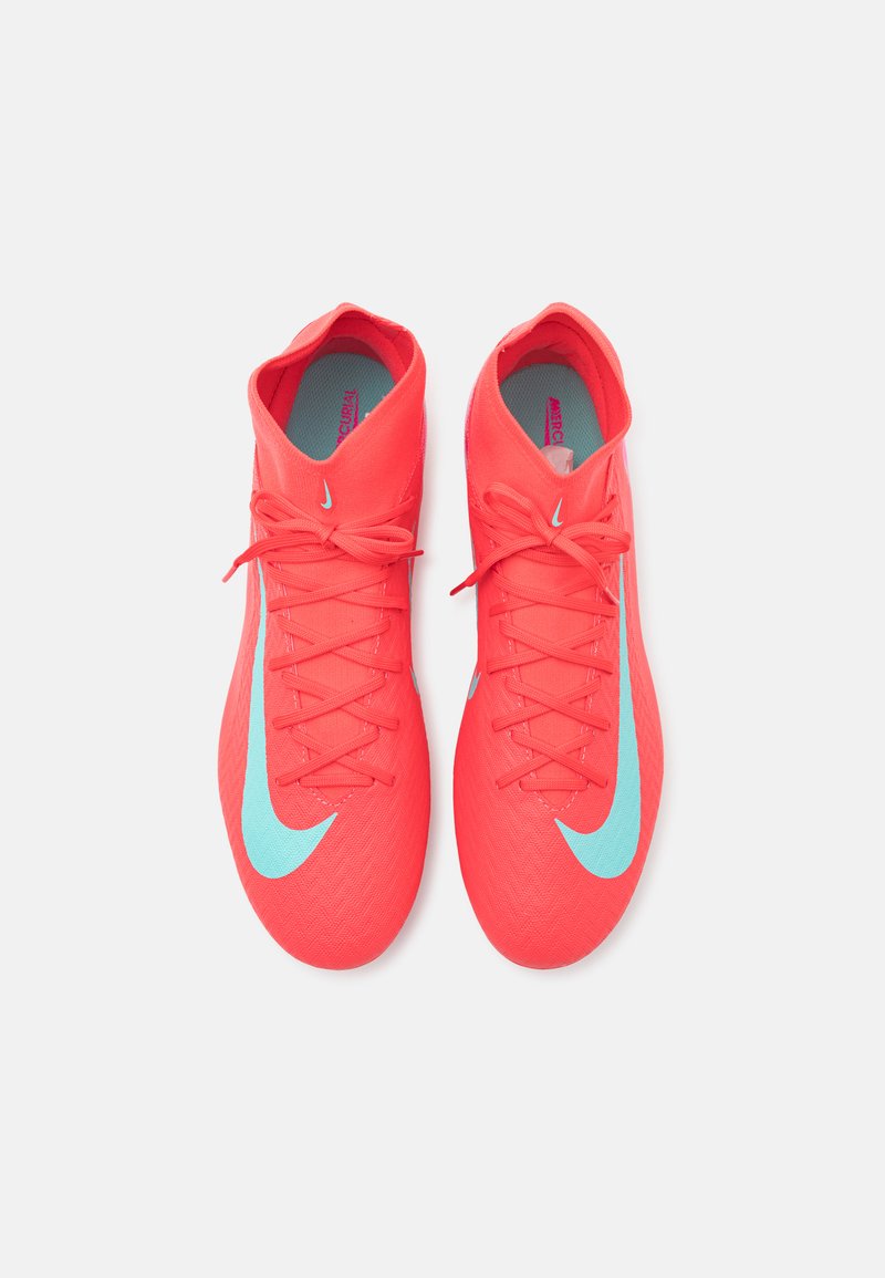 Chaussures de football Nike en corail vif avec une tige texturée, des accents turquoise et des lacets plats. Design élégant avec un col bas.